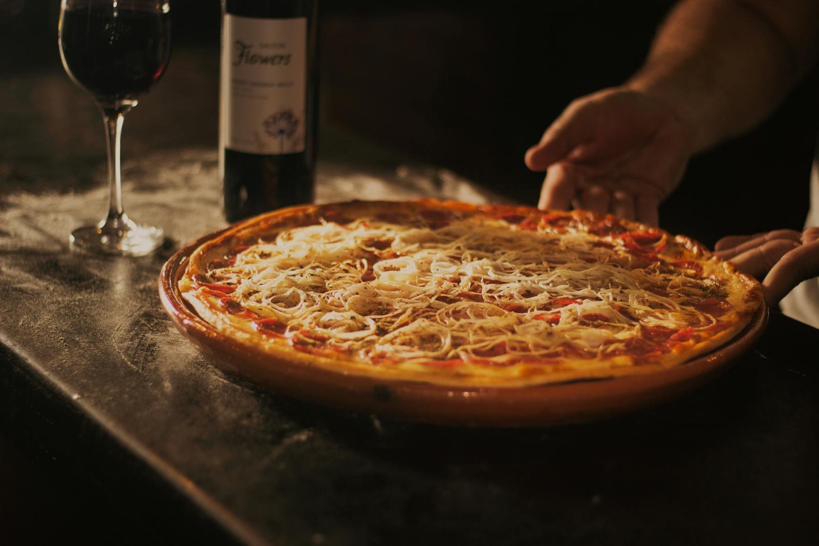 Delicious pepperoni pizza paired with red wine, showcasing a rustic dining experience in Centro, RJ.